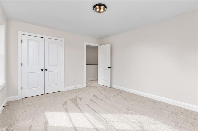 unfurnished bedroom with a closet and light colored carpet