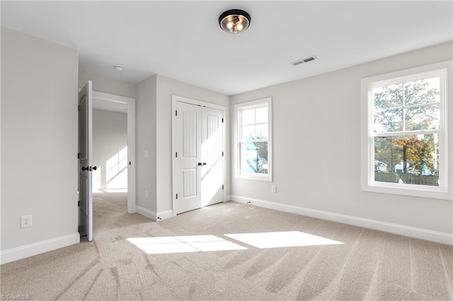 unfurnished bedroom with light carpet and a closet