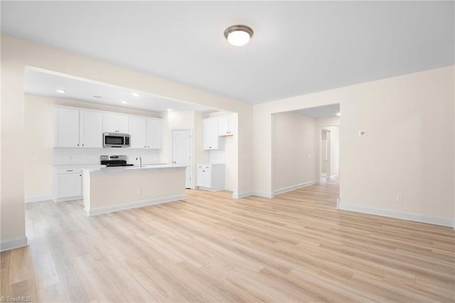 kitchen featuring sink, white cabinetry, light hardwood / wood-style flooring, appliances with stainless steel finishes, and an island with sink