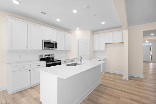 kitchen featuring white cabinets, appliances with stainless steel finishes, sink, and a kitchen island with sink