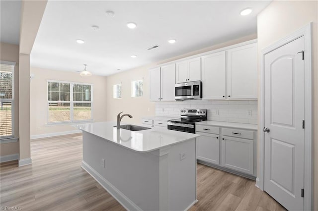 kitchen featuring white cabinetry, appliances with stainless steel finishes, sink, and a kitchen island with sink