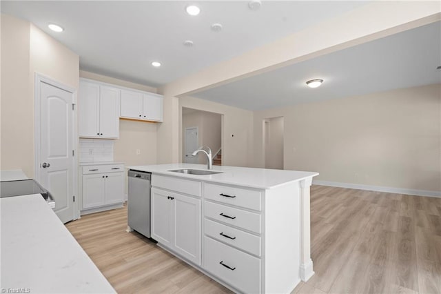 kitchen with stainless steel dishwasher, an island with sink, sink, and white cabinets