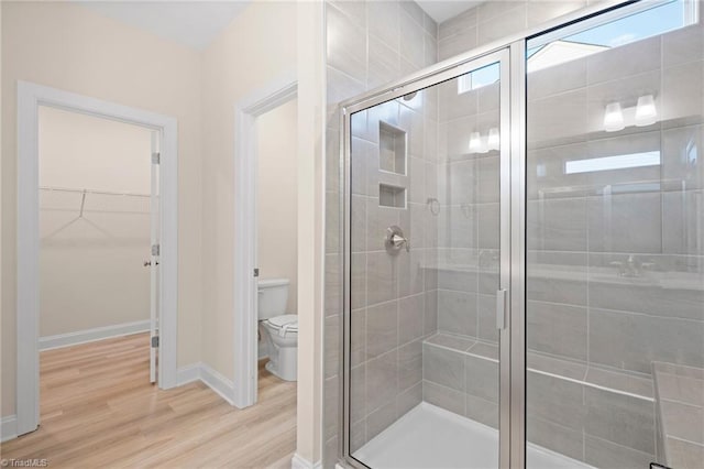 bathroom with toilet, a shower with shower door, and hardwood / wood-style floors