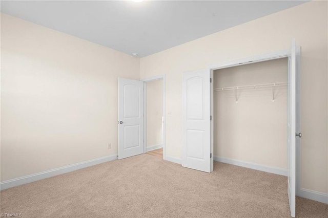 unfurnished bedroom featuring light colored carpet and a closet