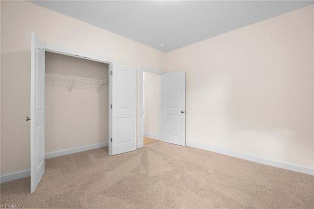 unfurnished bedroom with light colored carpet and a closet