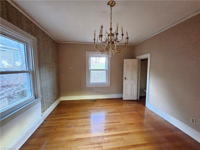 unfurnished dining area with hardwood / wood-style floors, ornamental molding, and a chandelier