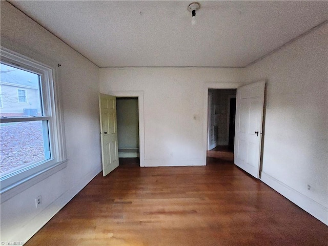 unfurnished bedroom with a textured ceiling and dark hardwood / wood-style flooring