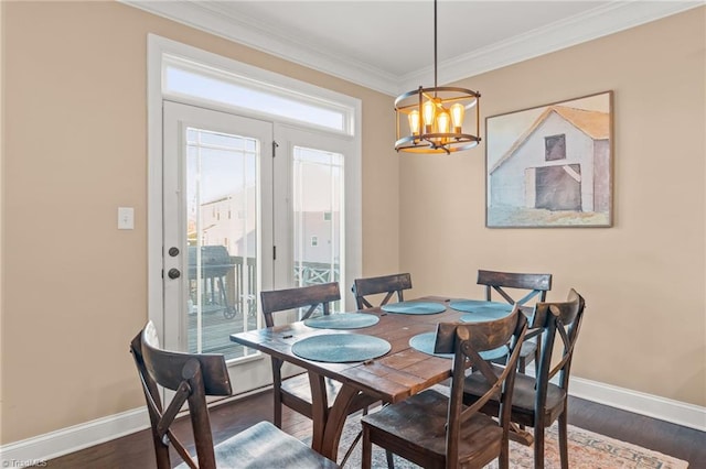 dining space featuring dark hardwood / wood-style flooring, ornamental molding, and a notable chandelier