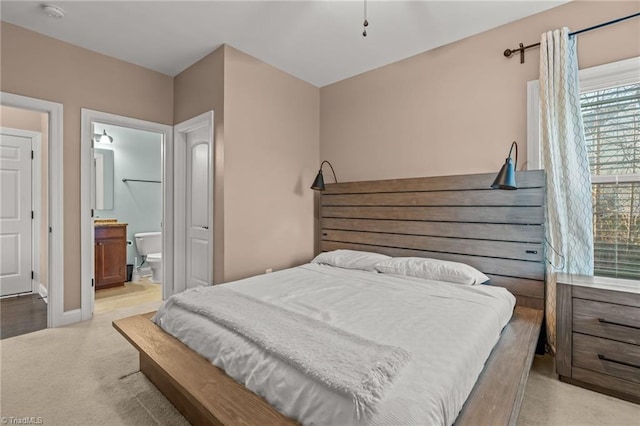 bedroom featuring light carpet and connected bathroom