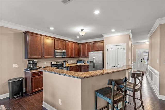 kitchen featuring appliances with stainless steel finishes, a kitchen island, crown molding, and a kitchen breakfast bar