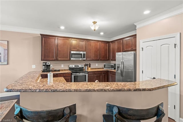 kitchen featuring a kitchen bar, crown molding, light stone counters, kitchen peninsula, and stainless steel appliances