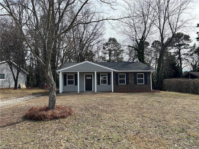 view of front of home featuring covered porch, brick siding, and a front lawn