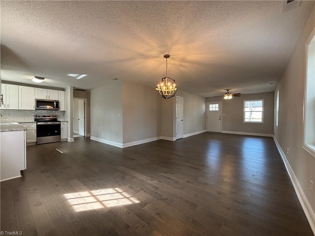 unfurnished living room featuring dark wood-style floors, baseboards, a textured ceiling, and ceiling fan with notable chandelier