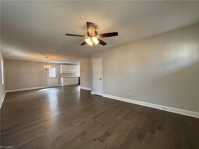 unfurnished living room featuring a ceiling fan, baseboards, and dark wood-type flooring