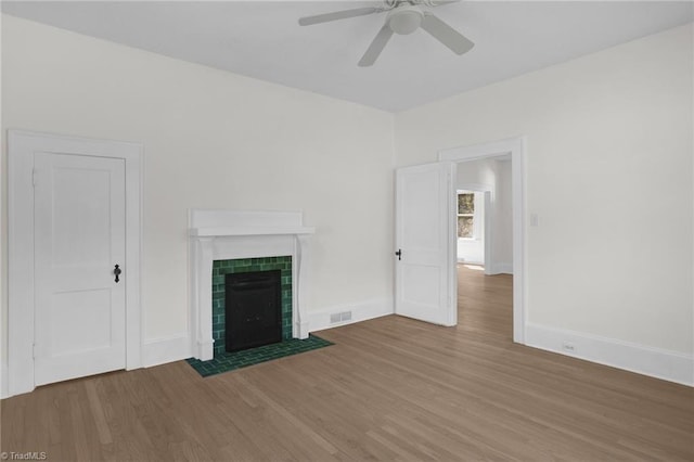 4221 Old Greensboro Rd, Winston-Salem, NC 27101 - unfurnished living room featuring wood finished floors, a ceiling fan, a tiled fireplace, and baseboards
