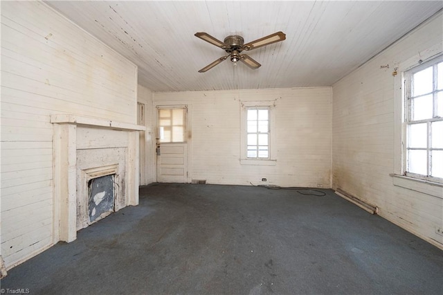 unfurnished living room with ceiling fan, a wealth of natural light, and a fireplace