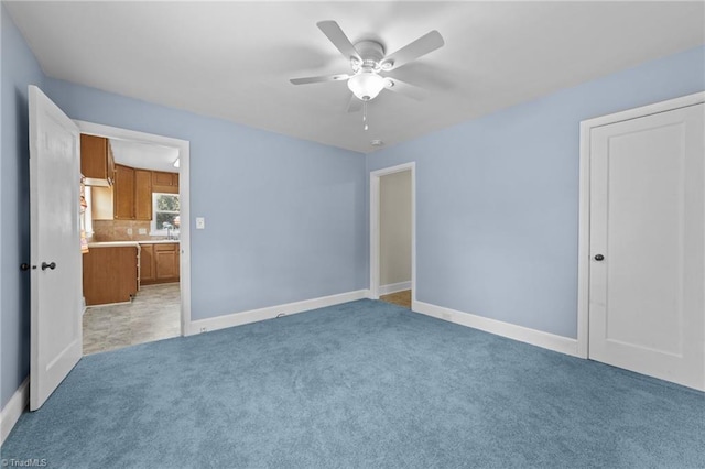 unfurnished bedroom featuring light colored carpet, ensuite bath, and ceiling fan