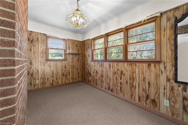 unfurnished room with carpet flooring, wooden walls, and an inviting chandelier