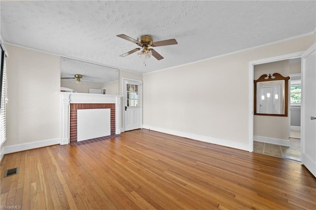 unfurnished living room featuring a textured ceiling, ceiling fan, hardwood / wood-style floors, and a brick fireplace