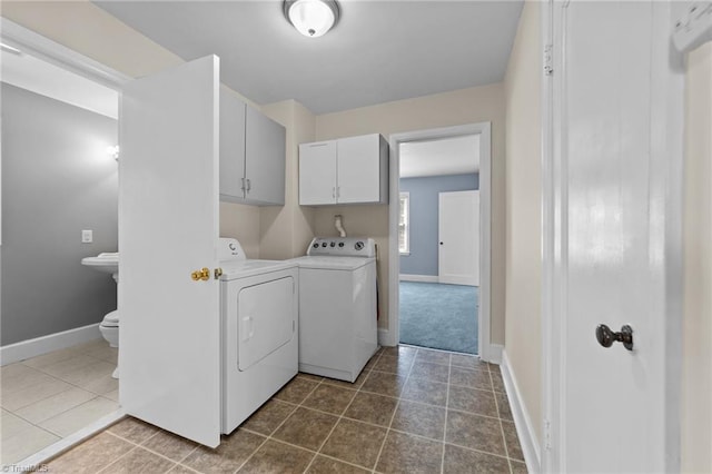 clothes washing area featuring tile floors, washing machine and clothes dryer, and cabinets