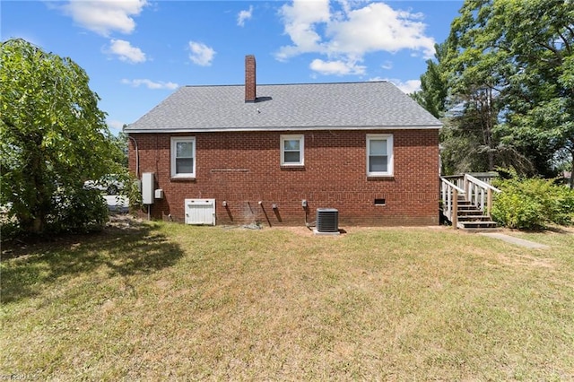 rear view of house featuring central AC unit and a lawn