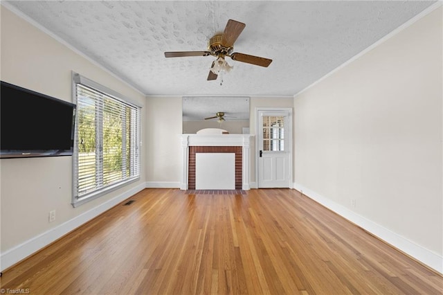 unfurnished living room with crown molding, a textured ceiling, a fireplace, light wood-type flooring, and ceiling fan