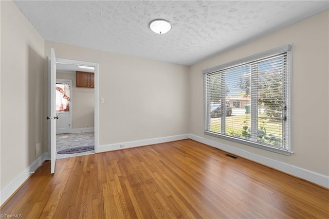 unfurnished room with wood-type flooring and a textured ceiling