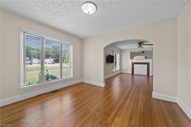 unfurnished living room with plenty of natural light, hardwood / wood-style flooring, and a textured ceiling