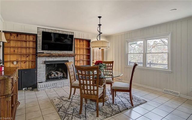 dining area featuring a fireplace, light tile patterned flooring, and ornamental molding