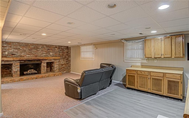 living room with a paneled ceiling and a brick fireplace