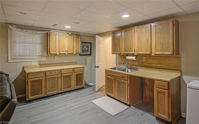 kitchen featuring a paneled ceiling, sink, and light hardwood / wood-style flooring