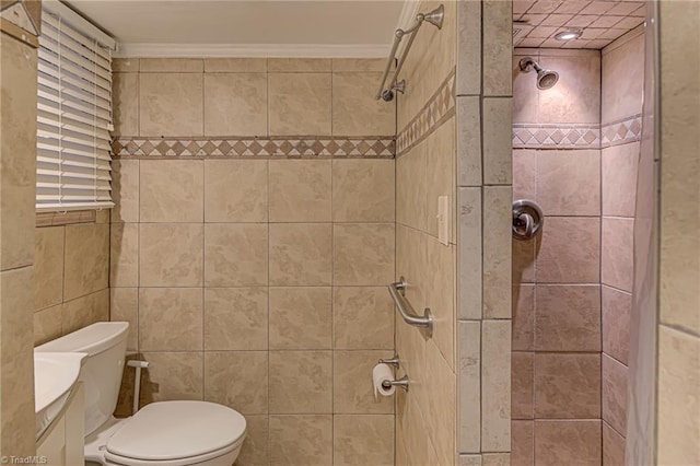 bathroom featuring vanity, toilet, ornamental molding, and a tile shower