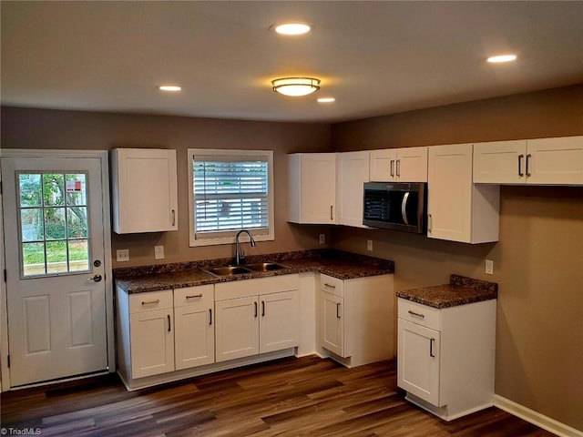 kitchen featuring white cabinetry, dark stone counters, dark hardwood / wood-style floors, and sink