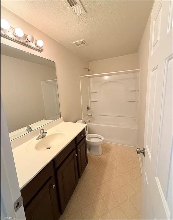 5608 David Christian Pl, Greensboro, NC 27410 - full bath with vanity, tile patterned floors, toilet, a textured ceiling, and shower / washtub combination