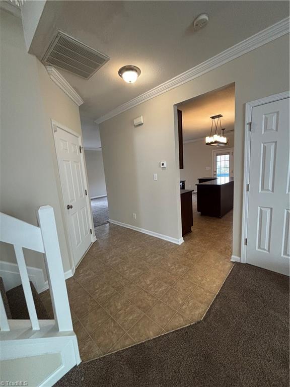 5608 David Christian Pl, Greensboro, NC 27410 - corridor featuring crown molding, baseboards, dark tile patterned flooring, and dark colored carpet