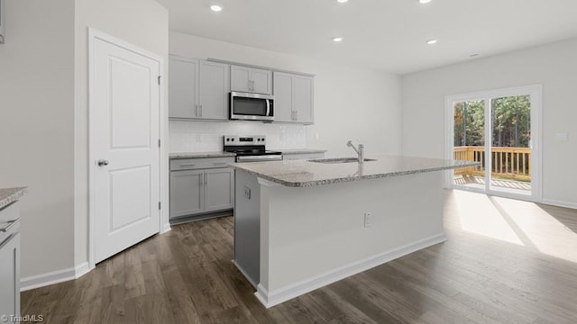 6601 Grogan Hill Rd, Whitsett, NC 27377 - kitchen featuring appliances with stainless steel finishes, dark wood-style flooring, tasteful backsplash, recessed lighting, and light stone counters