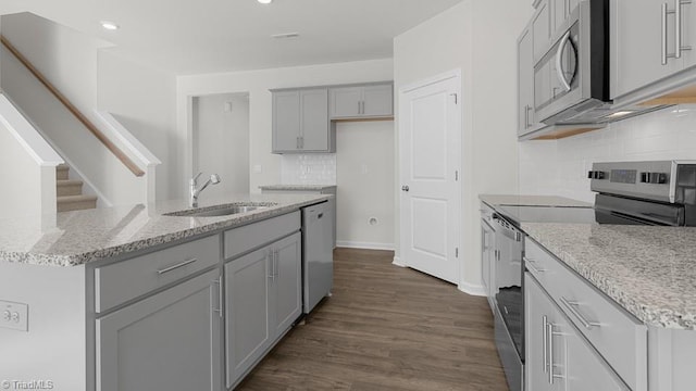 6601 Grogan Hill Rd, Whitsett, NC 27377 - kitchen with stainless steel appliances, gray cabinetry, a center island with sink, dark wood-style floors, and backsplash