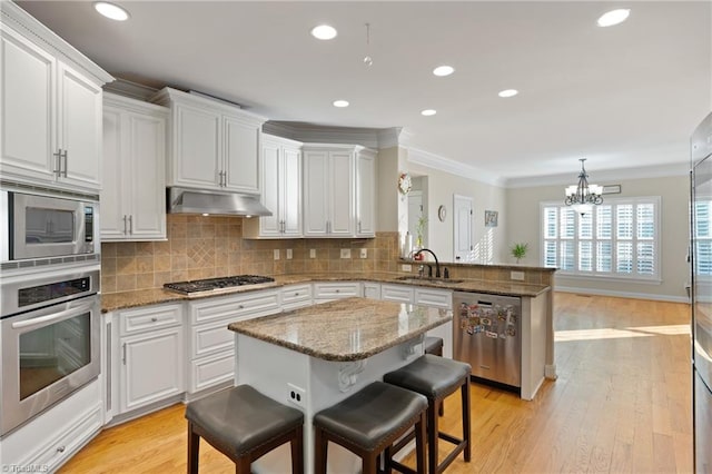 kitchen with a kitchen breakfast bar, kitchen peninsula, stainless steel appliances, ornamental molding, and tasteful backsplash