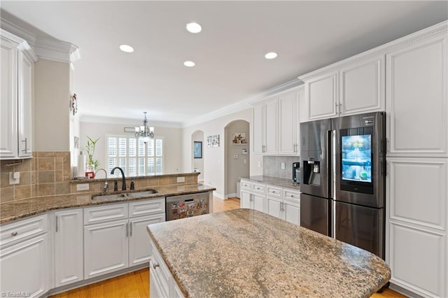 kitchen featuring sink, decorative backsplash, stainless steel appliances, white cabinets, and ornamental molding