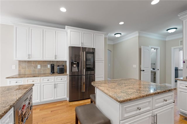 kitchen featuring light stone countertops, stainless steel fridge with ice dispenser, light hardwood / wood-style flooring, and white cabinets