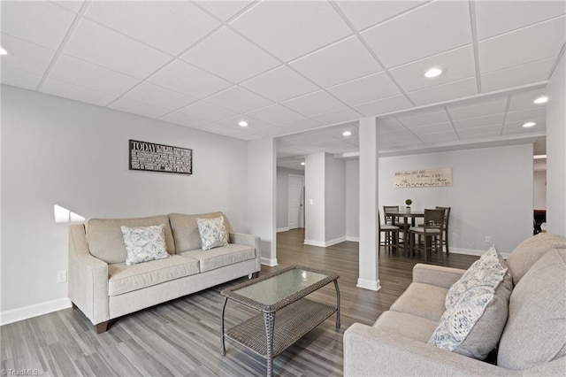 living room with a drop ceiling and wood-type flooring