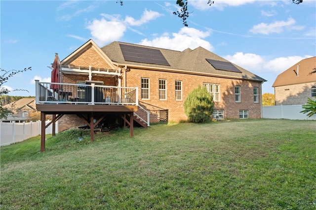 back of house featuring a yard, a deck, and solar panels