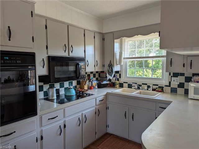 kitchen featuring a textured ceiling, black appliances, white cabinetry, sink, and backsplash