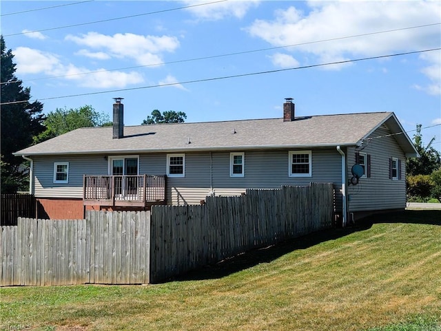 rear view of property with a wooden deck and a lawn