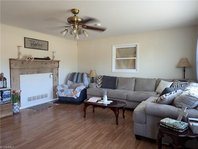 living room with ceiling fan, a textured ceiling, and dark hardwood / wood-style floors