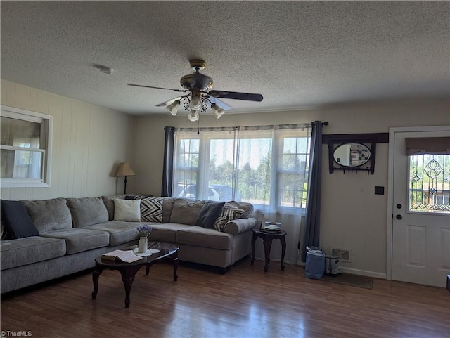 living room with ceiling fan, dark wood-type flooring, and a textured ceiling