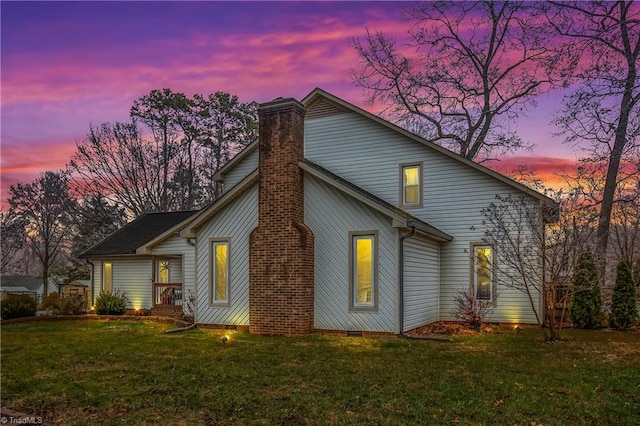 back house at dusk featuring a yard