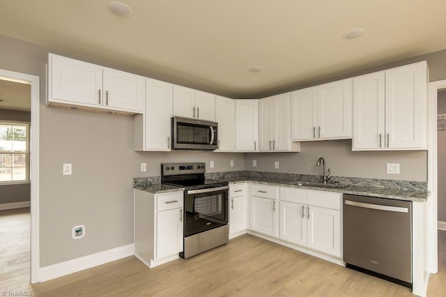 kitchen featuring sink, appliances with stainless steel finishes, white cabinetry, light stone countertops, and light hardwood / wood-style floors