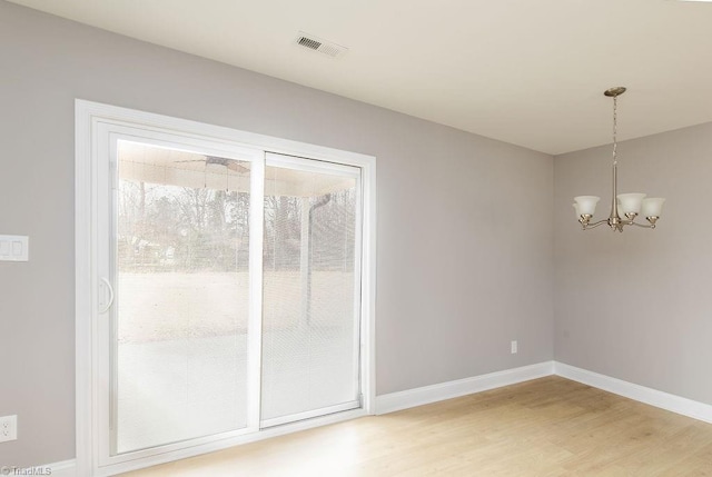 unfurnished dining area with an inviting chandelier and wood-type flooring