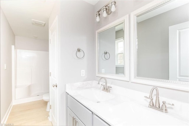 bathroom with a shower, hardwood / wood-style floors, vanity, and toilet